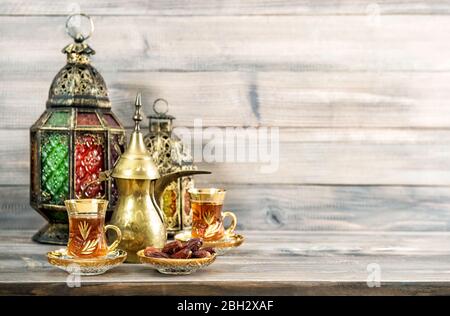 Tea glasses with dates and oriental lantern decoration on wooden background Stock Photo