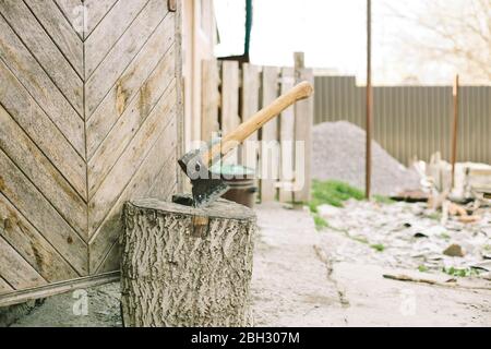 Ax stuck in the wooden stump. Woodcutter's ax on the stump. Stock Photo