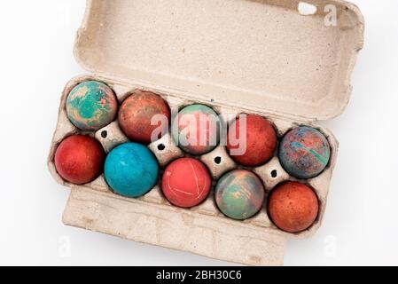 Colorful Easter eggs in cardboard egg box on white background. Raw chicken eggs in open egg box on a white background. Eggs in the package. Stock Photo