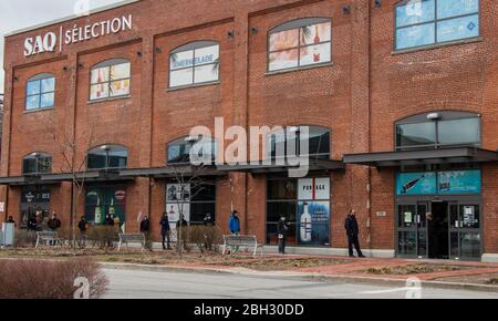 April 11, 2020 -  Montreal, Qc, Canada: Customers waiting in line in front SAQ Angus Liquor Wine Store during Coronavirus COVID-19 Pandemic Stock Photo