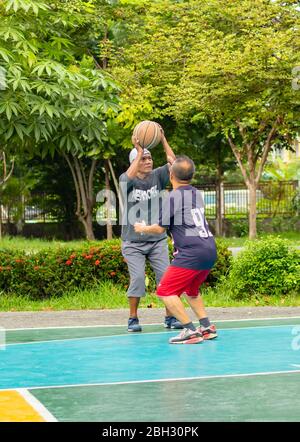 Old man happy with exercise to play basketball at BangYai  Park  Nonthaburi in Thailand. August 22, 2018 Stock Photo