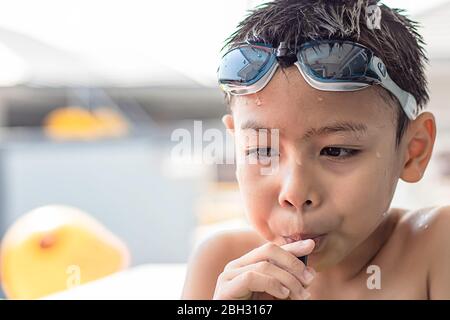 Portrait Asian boy holding Drinking straws and wearing swimming goggles