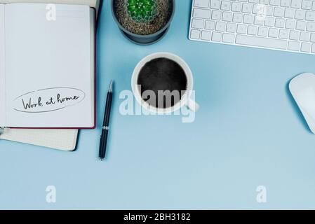 work from home and home office concept, top view of clean modern desktop with potted plant, computer keyboard, mouse and notebooks Stock Photo