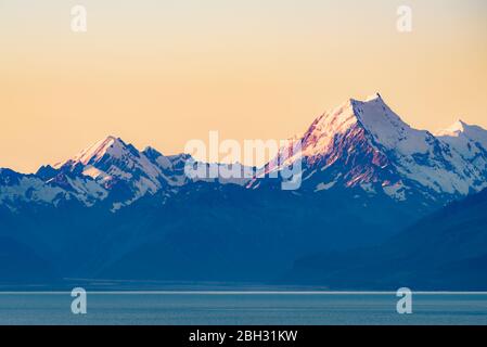 Beautiful landscape of Mount Cook peak covered in snow at dusk after sunset seen across Lake Pukaki. Aoraki / Mount Cook National Park, New Zealand. Stock Photo