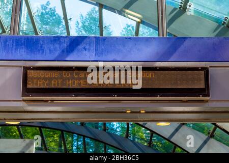 19th April 2020 - London, UK, LED display at Canary Wharf Underground Station entrance saying 'Stay at home, save lives' during the Coronavirus pandemic lockdown Stock Photo