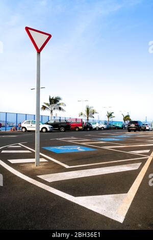 A yield sign in a parking lot with disabled parking space marked with blue International Symbol of Access (ISA). Stock Photo