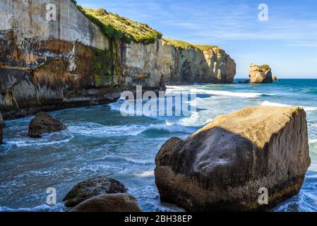 Sculpted cliffs, eroded rock formations and rough sea waves at Tunnel Beach, Otago region, South Island, New Zealand Stock Photo