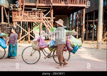A Cambodian lady sells vegetables from her bicycle  along the main road at the floating village of Kampong Phluk, near Tonle Sap Lake, Cambodia. Stock Photo
