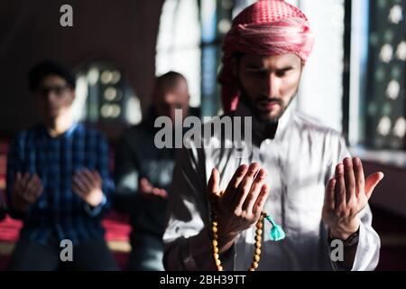 Group of young Muslim people praying. Muslim prayers doing a pray inside the mosque. Stock Photo