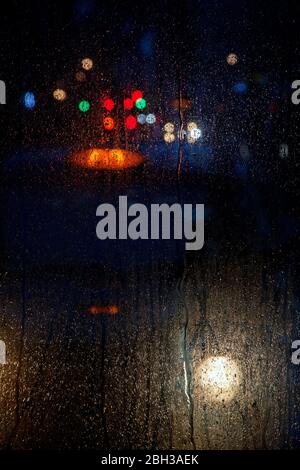 lights reflected in bus window on rainy night Stock Photo