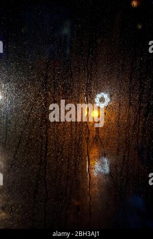 lights reflected in bus window on rainy night Stock Photo