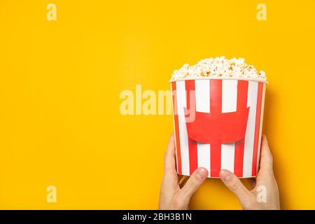 The guy holds popcorn in his hands on a yellow background. Place for text. Stock Photo