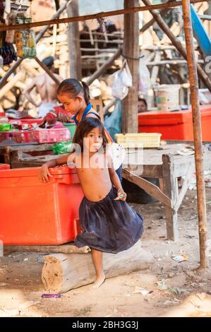 Two young Cambodian girls enjoy a snack and break as they play in the