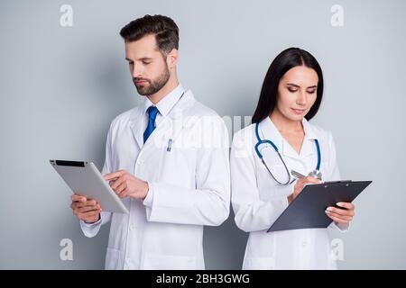 Photo of handsome busy family doc guy medic lady virology clinic experienced doctors writing prescription online e-book paper clipboard wear lab coats Stock Photo