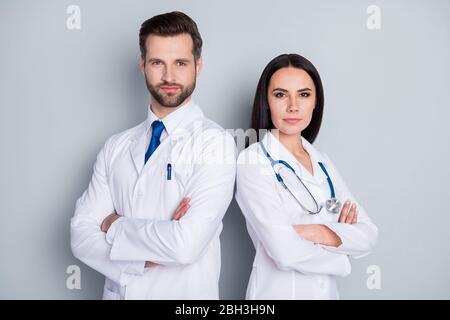 Photo of handsome doc guy medic lady emergency patient consultation virology clinic stand back-to-back arms crossed experienced doctors wear lab coats Stock Photo