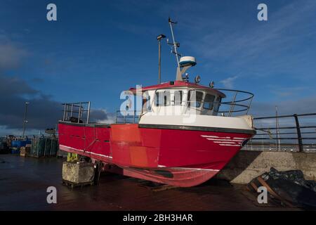 Red fishing trawler on dock for repairs Stock Photo