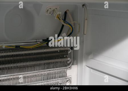 the master removed the refrigerator freezer fan for repair, looks at the cooling radiator, disconnected the fan connector, the master for an hour Stock Photo