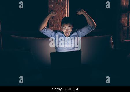 Portrait of his he nice attractive lucky excited glad childish cheerful cheery guy sitting on divan using laptop having fun at modern loft industrial Stock Photo