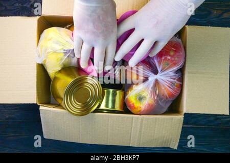 Packed various food items in donation box for the poor. Canned food, cooking oil, eggs, fruits, pasta. Top view, flat lay. Close-up. Indoors. Stock Photo