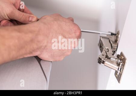 Handyman Installing Hardware In Kitchen Cabinets Using Screwdriver. Stock Photo