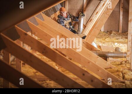 HVAC Worker Installing Heating And Air Conditioning System In Insullated House Attic. Stock Photo