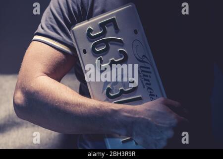 Caucasian Male Holding License Plate From Car In Illinois. Stock Photo