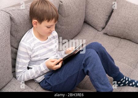 Distance learning online education. Looking up young boy thinking in front of tablet pc. Stock Photo