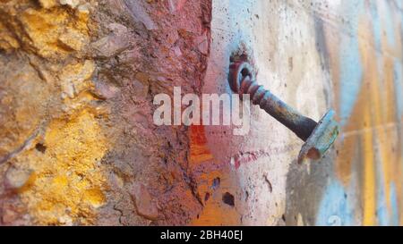 A condemned building in a state of urban decay shows the passing of time with this loose rusty bolt in an exterior wall Stock Photo