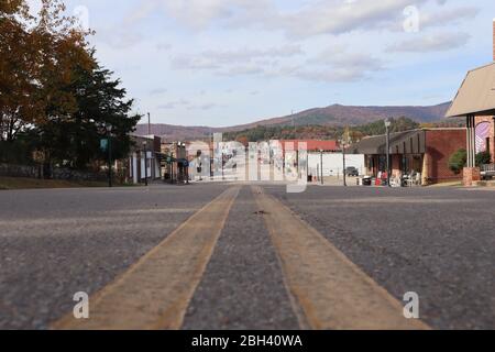 A street-level perspective view down a small town main street, Mena Street, Mena, Arkansas, with autumn colors on Rich Mountain in the background Stock Photo