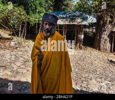 Bahir Dar, Lake Tana, Ethiopia - February 12, 2015: Priest walking with cane in front of the Monastery on the island, Lake Tana, Ethiopia. Stock Photo
