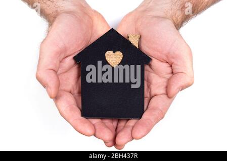 A man holds in his hands a flat model of a house on a white background. Family loan concept Stock Photo