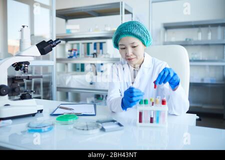 Asian nurse sitting at the table and examining the results of blood samples in the lab Stock Photo