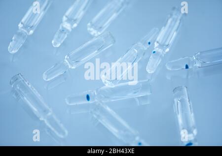 Close-up of glass capsules with medicine inside of it isolated on blue background Stock Photo