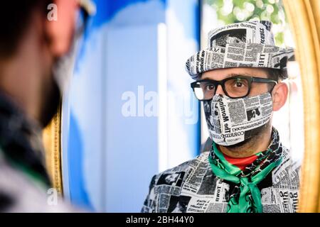 Berlin, Germany. 23rd Apr, 2020. Italian hatter GIUSEPPE TELLA checks the fit of his face mask in a mirror in his studio in Berlin. Tella and his partner produce individual, elaborate hat fashion from high-quality materials. In the the course of the worldwide Covid-19 pandemic they have expanded their production to include face masks. Credit: Jan Scheunert/ZUMA Wire/Alamy Live News Stock Photo