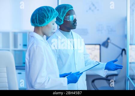 Two medical workers in white coats talking to each other while working together at hospital Stock Photo
