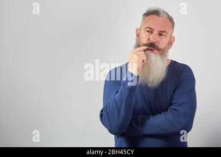 Portrait of pensive mature gray-haired bearded man on gray background, selective focus Stock Photo