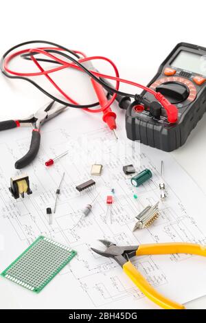 Different electronic parts or components, measurement tool and pliers on white background with pcb wiring diagram, resistors, capacitors, diode and ic Stock Photo