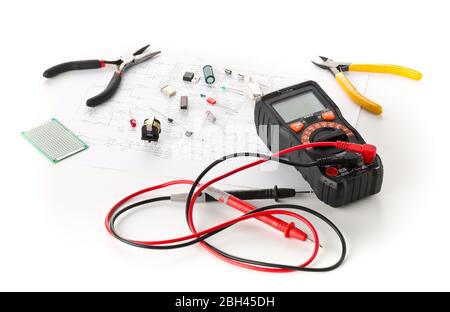 Different electronic parts or components, measurement tool and pliers on white background with pcb wiring diagram, resistors, capacitors, diode and ic Stock Photo