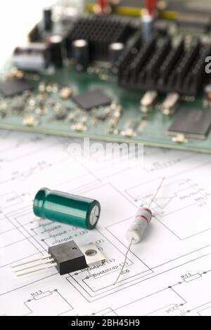 Transistor, resistor and capacitor electronic parts or components in front of pcb board with pcb wiring diagram - electronic device repair concept, se Stock Photo