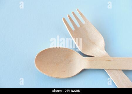 Eco cutlery from pine wood. Disposable tableware from natural materials. Wooden spoon and fork on a pastel blue background. Image with copy space. Stock Photo