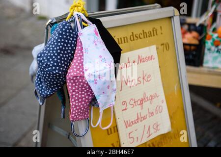 Berlin, Berlin, Germany. 23rd Apr, 2020. Hand made, patterned masks for sale hanging over a sales sign in Berlin Schoeneberg. From April, 27 people in Berlin have to wear a face mask in city buses, subway and underground trains. Also in the partly reopened retail sector and in contact with persons at risk, such protection is only strongly recommended. As there is still a lack of respiratory masks and protective equipment among doctors and hospitals, many entrepreneurs offer self-made, non-medical masks for sale. Credit: Jan Scheunert/ZUMA Wire/Alamy Live News Stock Photo