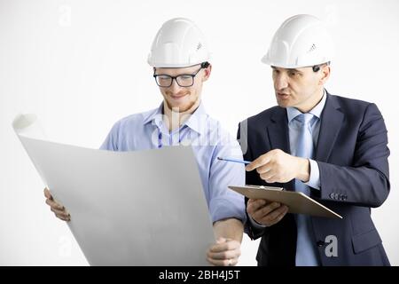 Two positive construction engineers look at drawing, making notes on clipboard Stock Photo