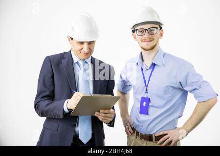 Two engineers different ages look at camera smiling, making notes on clipboard Stock Photo