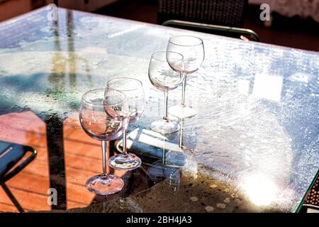 Terrace patio in Italy with four wine glasses on empty glass table with transparent view in winery or vineyard Stock Photo