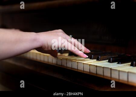 Old forte piano with female woman hand and diamond ring finger pianist playing closeup for concert with black background Stock Photo