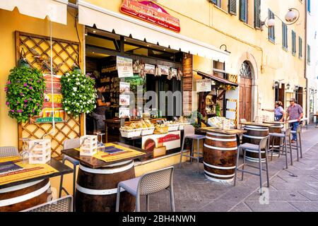 Castiglione del Lago, Italy - August 28, 2018: Alley street in small town village in Umbria during day on sunny summer day with people shopping by yel Stock Photo