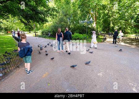 London, UK - June 21, 2018: Saint James Park in sunny summer with many people walking on sidewalk by pigeon birds wide angle view Stock Photo