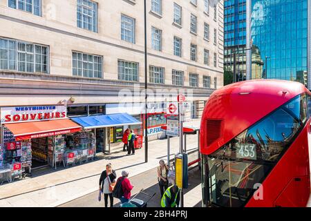 London, UK - June 22, 2018: Above high angle view on bus stop with people on street sidewalk and information sign for St Thomas Hospital County Hall