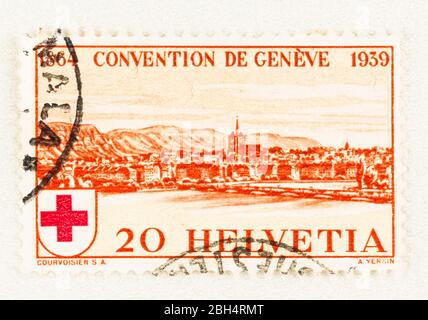 SEATTLE WASHINGTON - April 18, 2020:  Red Swiss postage stamp with view of Geneva, commemorating 75th anniversary of International Red Cross Society. Stock Photo