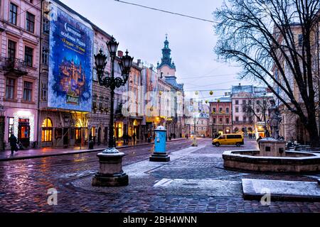 Lviv, Ukraine - December 28, 2019: Old town market square fountain in Lvov with winter Christmas illumination and empty rynok at morning night with sn Stock Photo